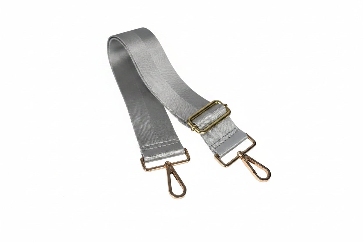 A silver satin strap with gold-toned metal hardware, including a buckle, loops, and swivel clips, shown on a plain white background.
